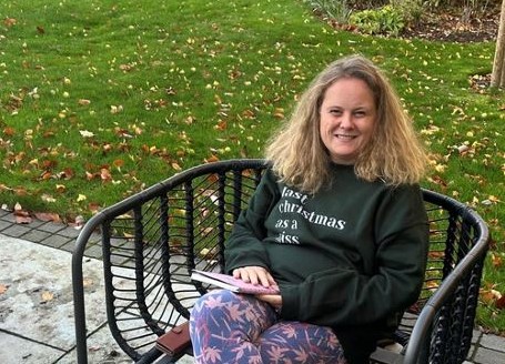 Lucy, service user sitting on a bench smiling at the camera