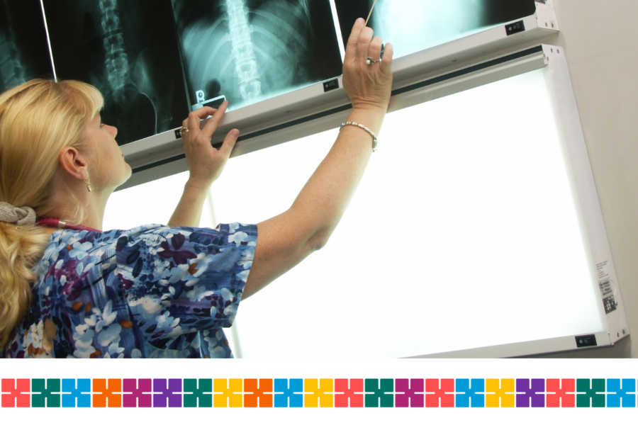Female clinician with blonde hair looking up at a selection of x-ray scans.