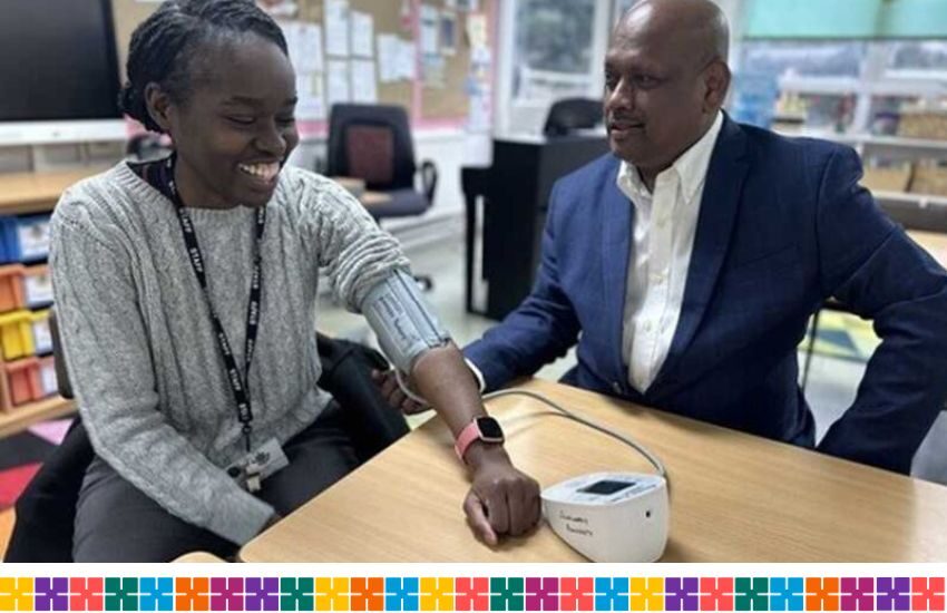 Two people smiling at each other, one has a blood pressure monitor on